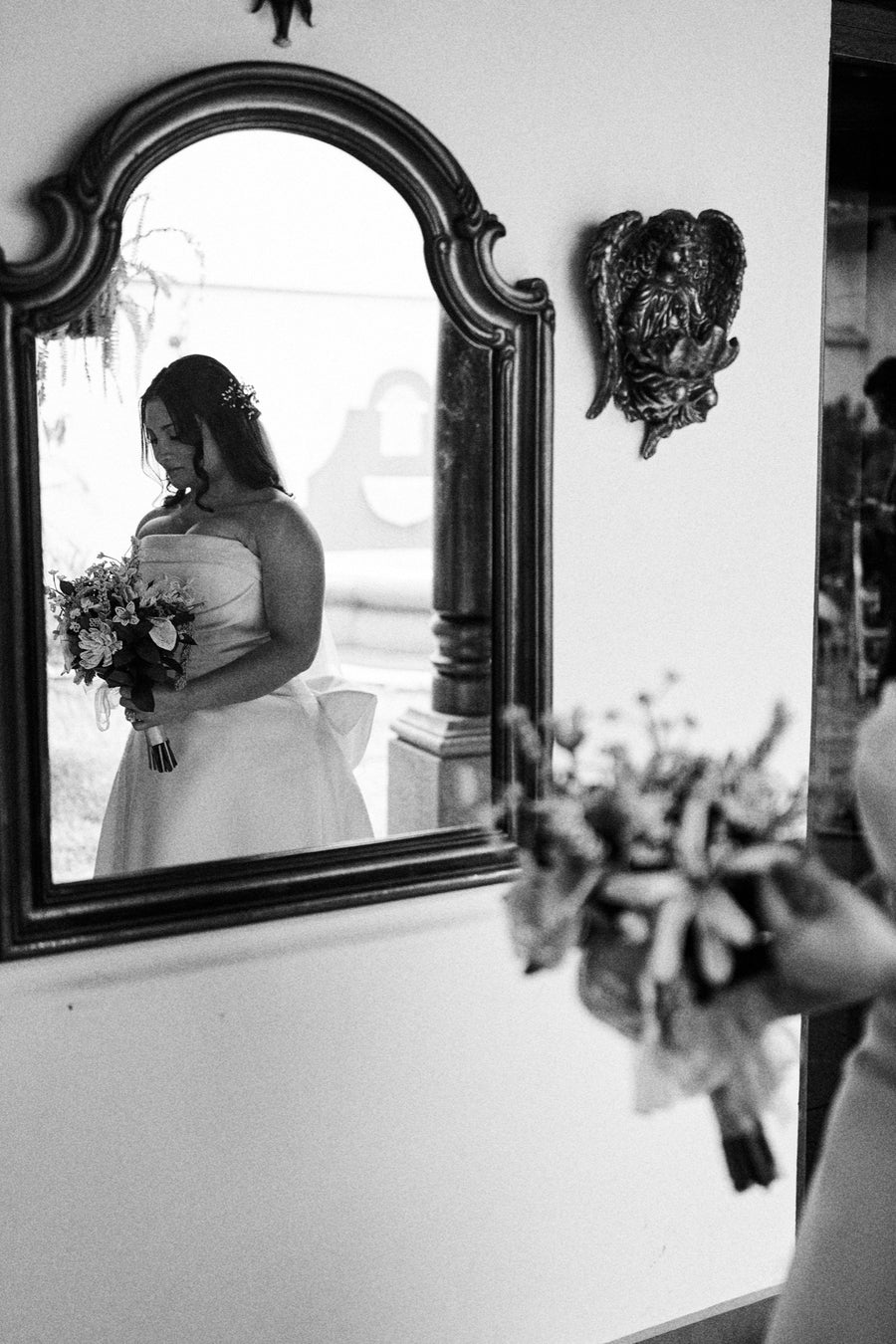 Nathalia on her wedding day, reflected in a mirror, holding her handmade French beaded bouquet
