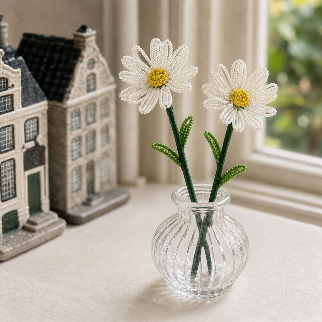 Two finished handmade beaded daisy stems displayed in a small glass vase