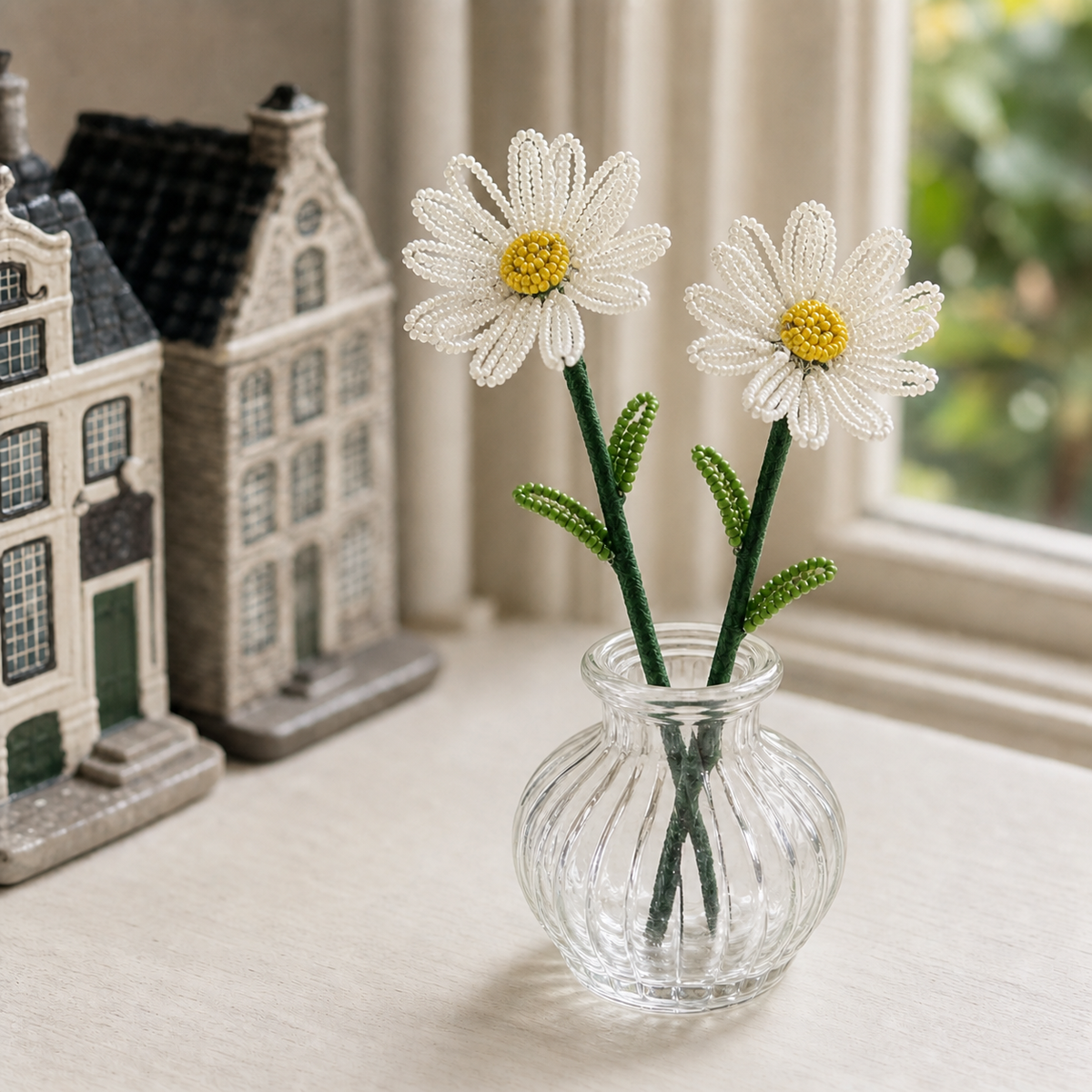 Two finished handmade beaded daisy stems displayed in a small glass vase