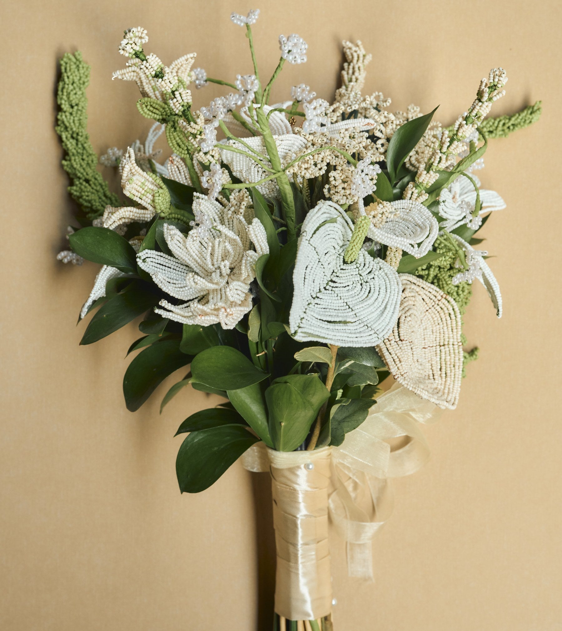 A finished bouquet of handmade beaded flowers beside an open flower kit